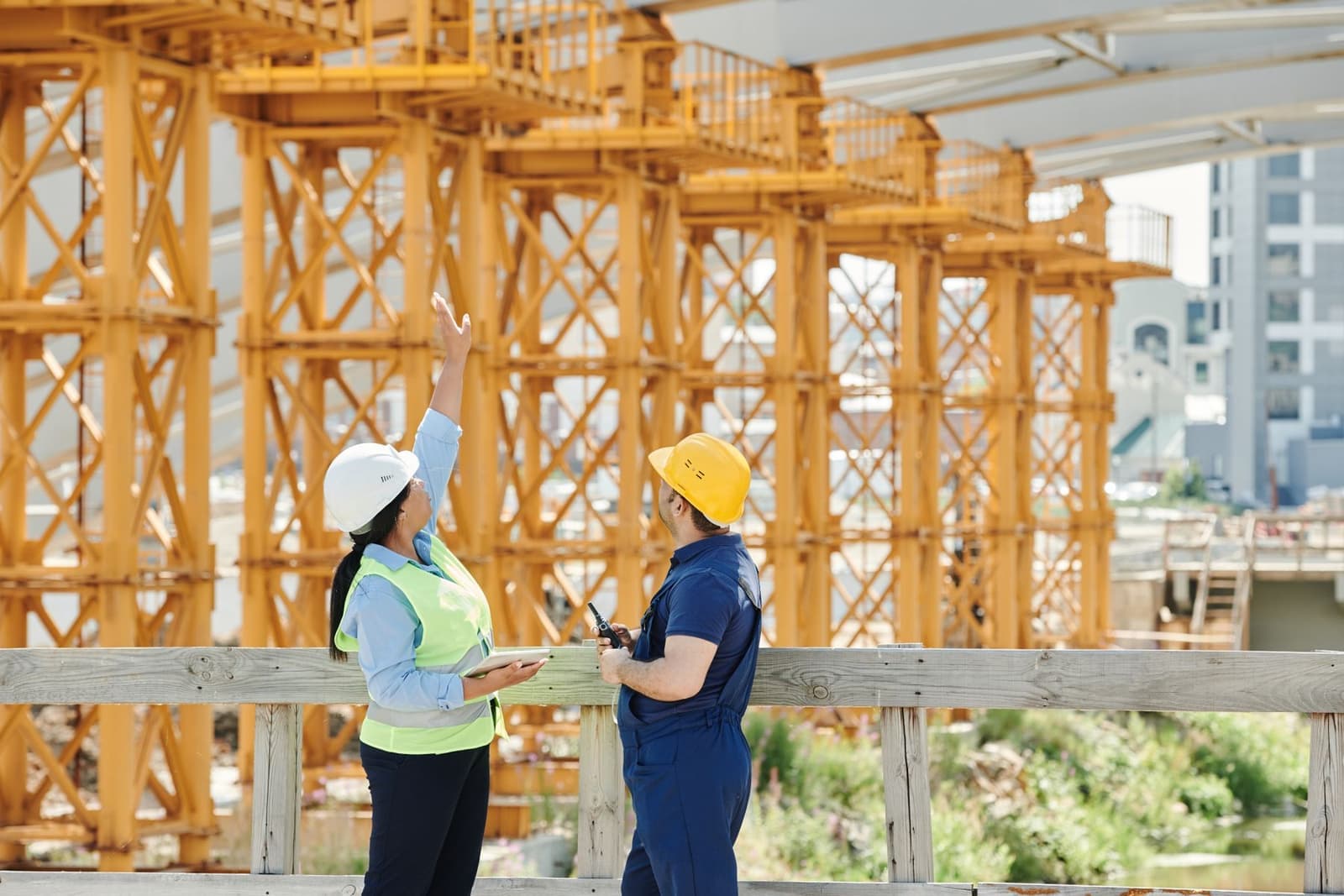 Two workers in hi-vis walking a timber-frame construction site