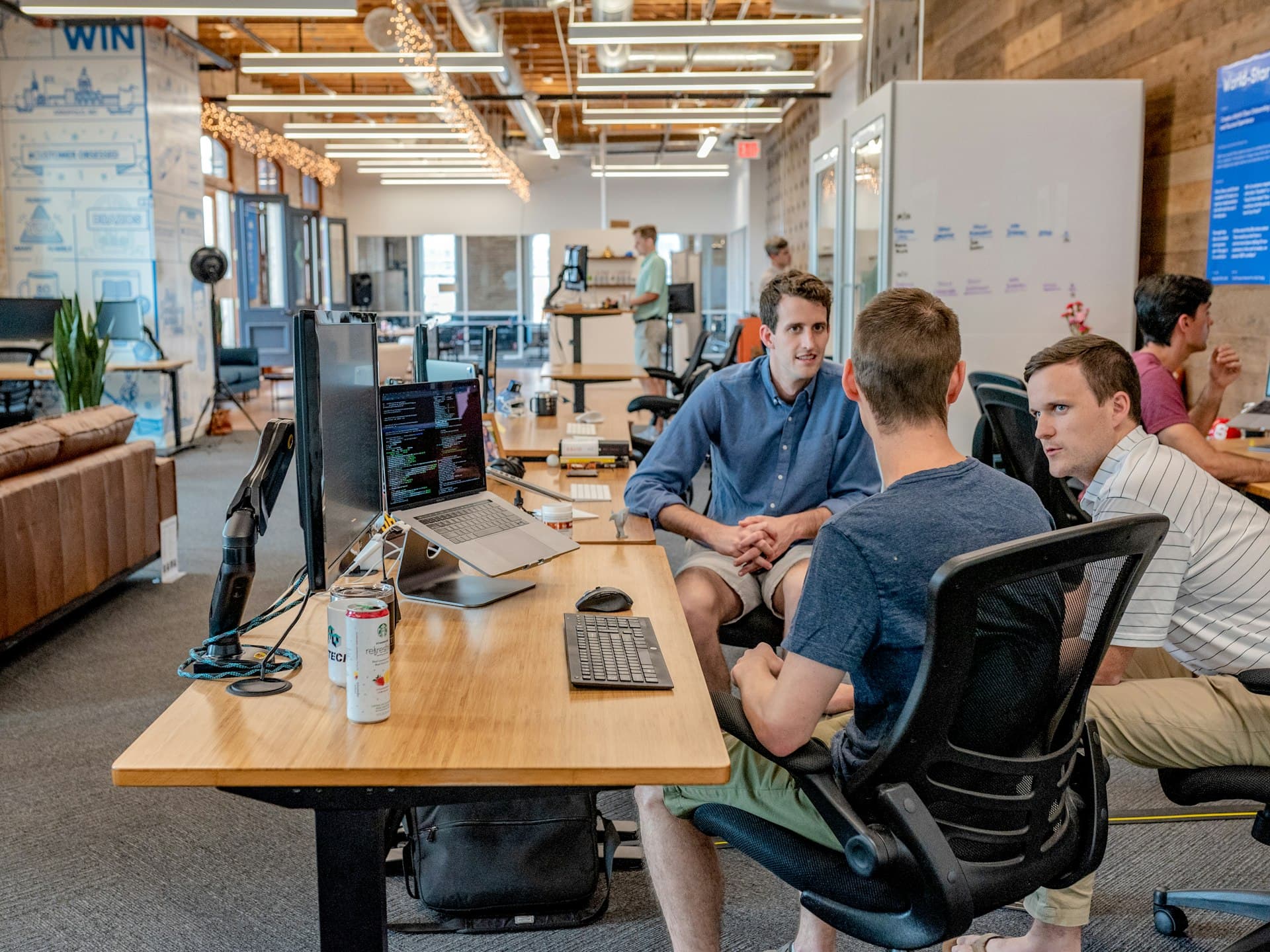 Colleagues in casual clothes talking through a project at their desks in an open-plan office