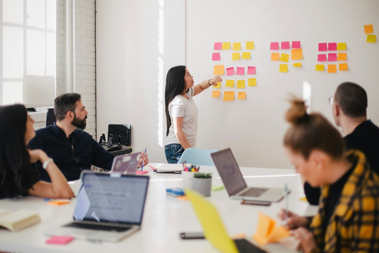 A colleague grouping sticky notes on a wall while the team maps skills together