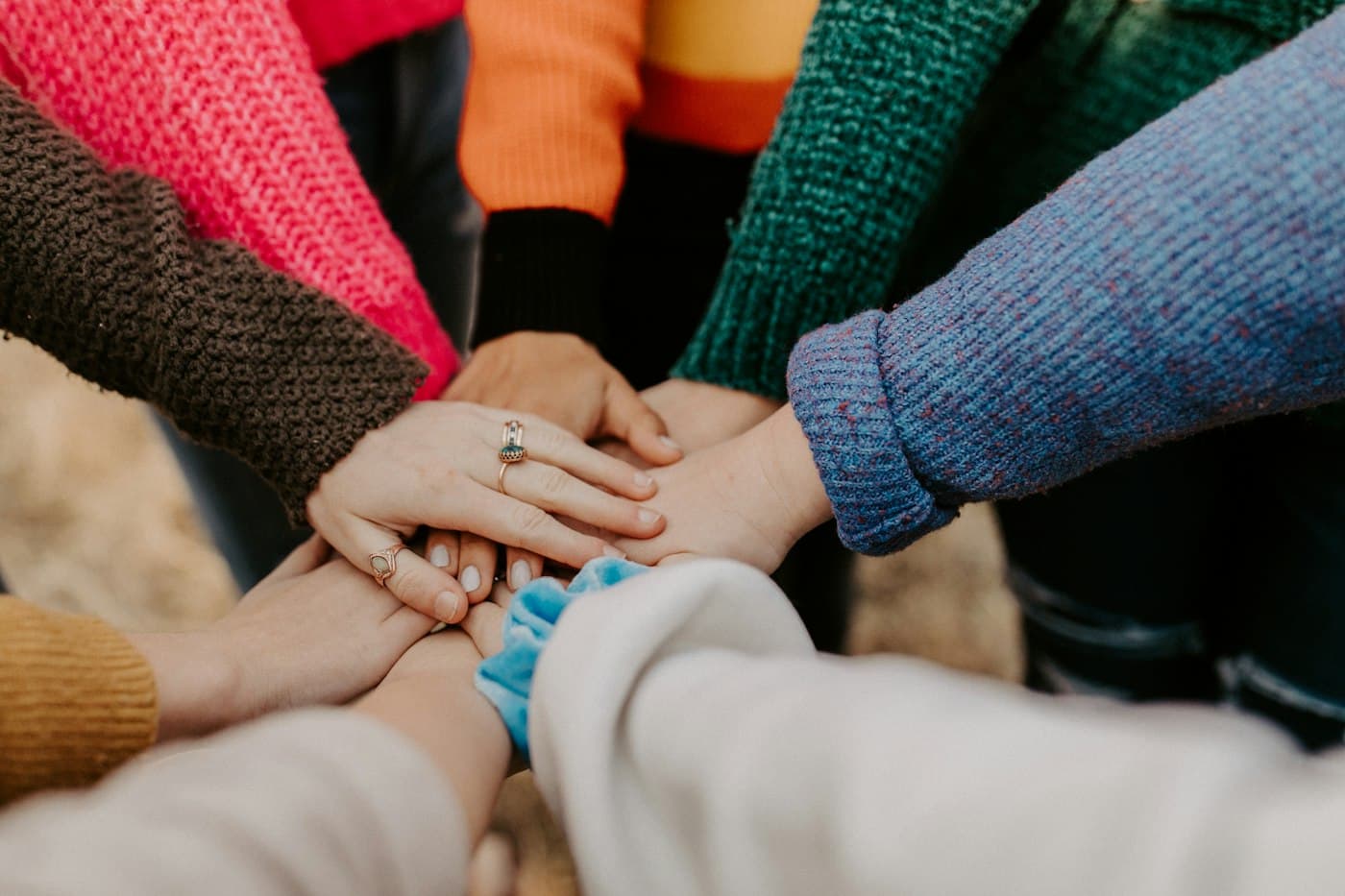 Colleagues in knitwear stacking their hands together