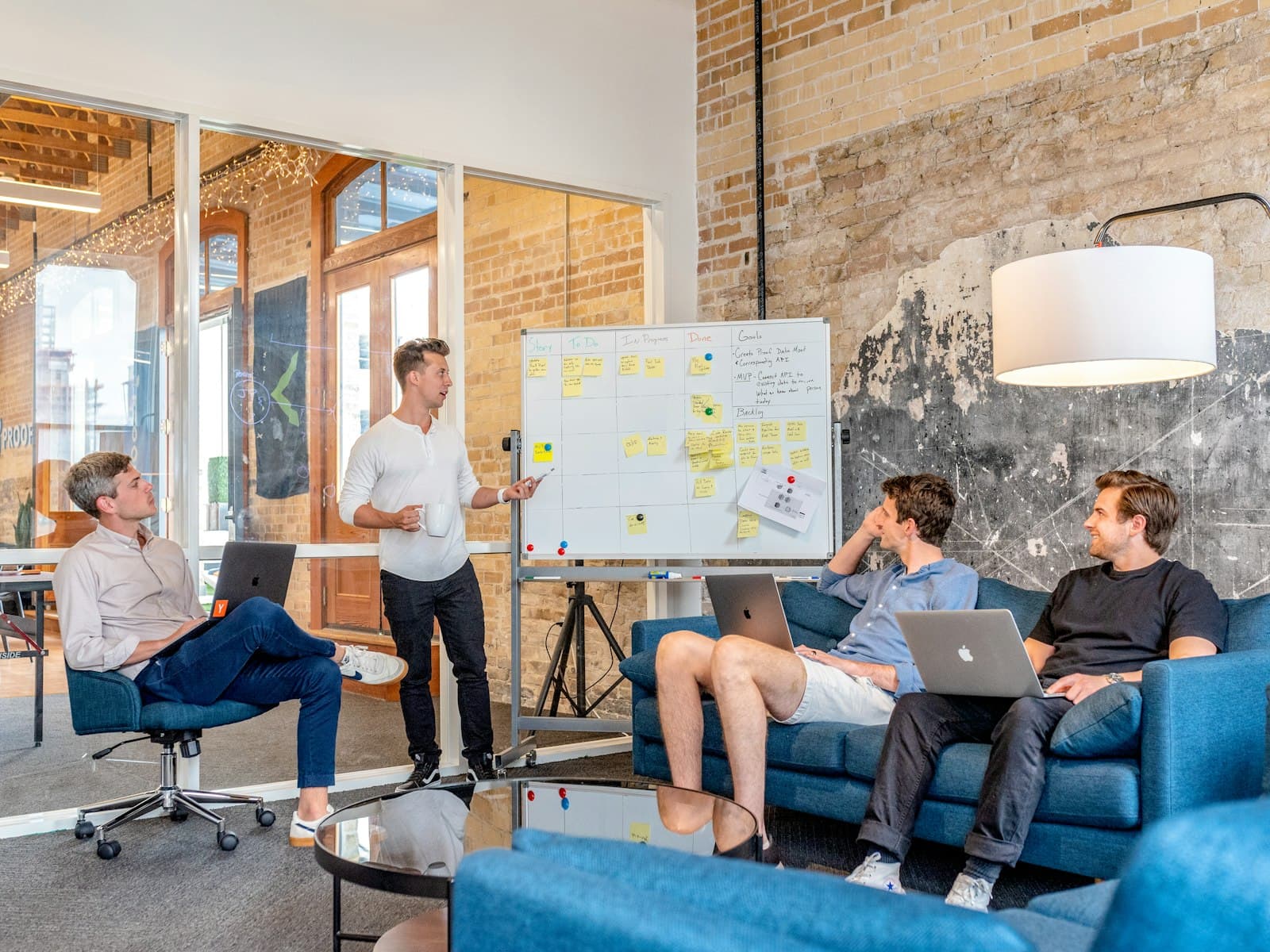 An adviser leading a whiteboard workshop with a small team on sofas